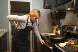 A mature woman experiencing backache at home in the kitchen